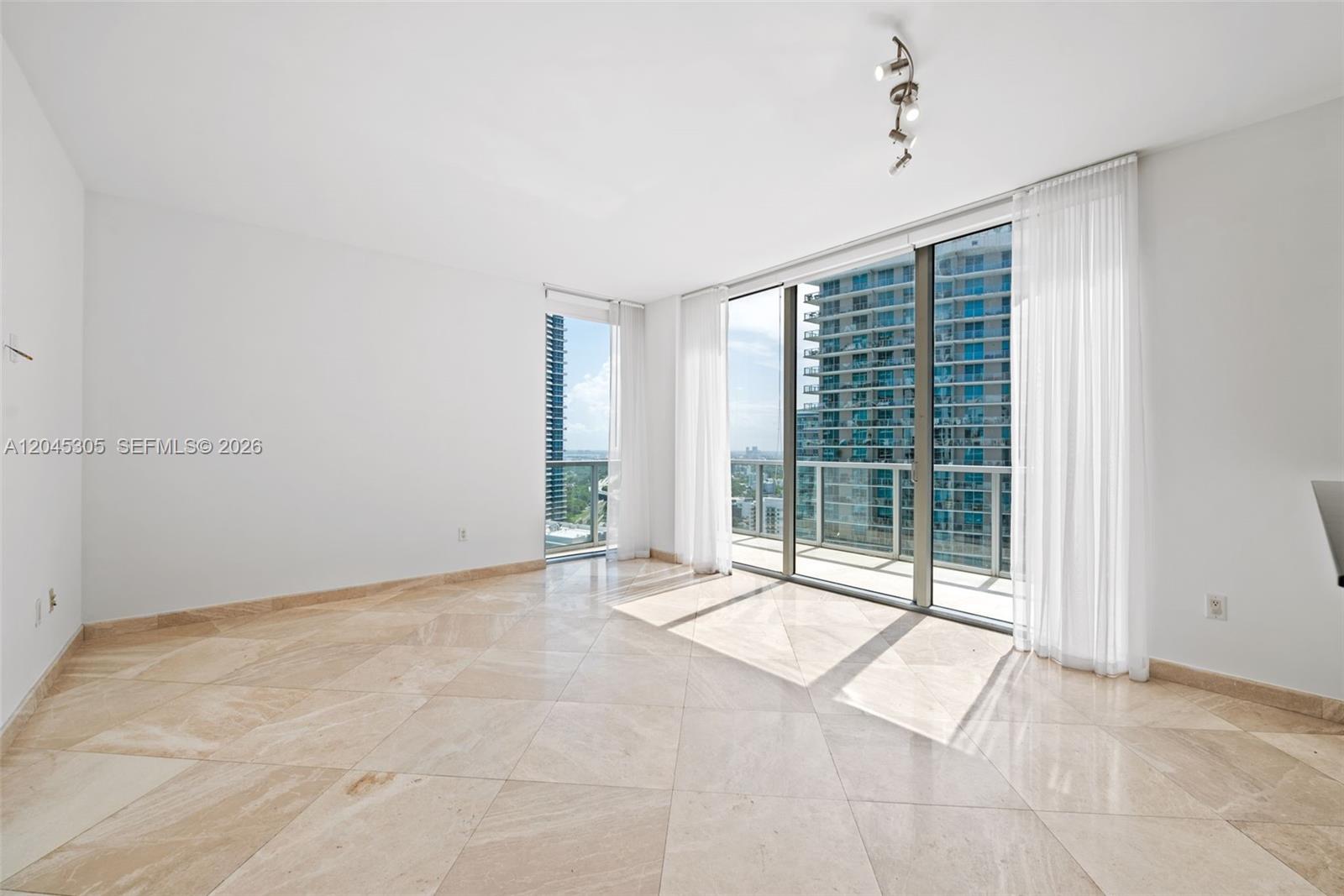 An empty room features light-colored tile flooring, white walls, and floor-to-ceiling windows with balcony access — 1050 Brickell Ave # 3314, Miami FL 33131, MIAMI, FL