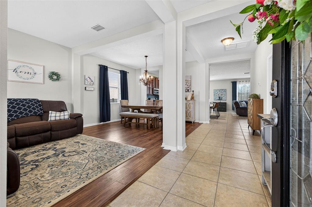 A view from an entryway showing a living room with wood floors and tiled hallway — 9634 OAK GLADE AVENUE, TAMPA, FL