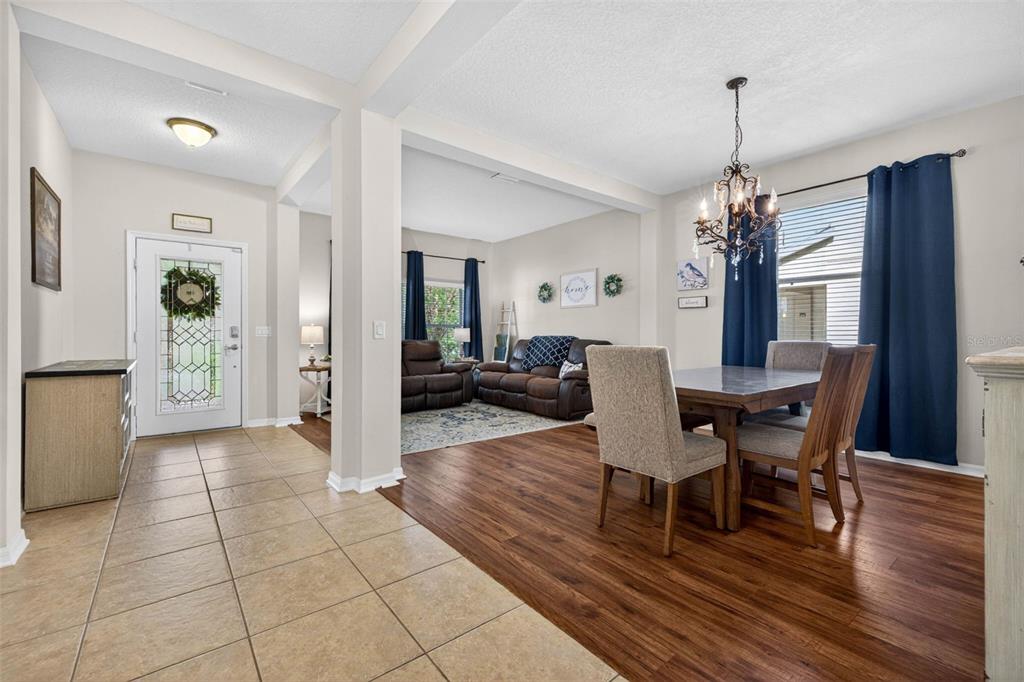 A dining area with a chandelier and wood floors leads into a tiled entryway — 9634 OAK GLADE AVENUE, TAMPA, FL