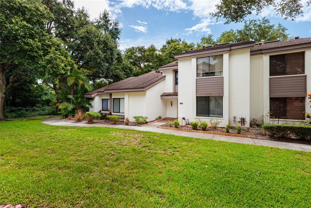A two-story residential building with white stucco walls, brown trim, and a grassy lawn — 1750 LAKE CYPRESS DRIVE UNIT 1002, SAFETY HARBOR, FL