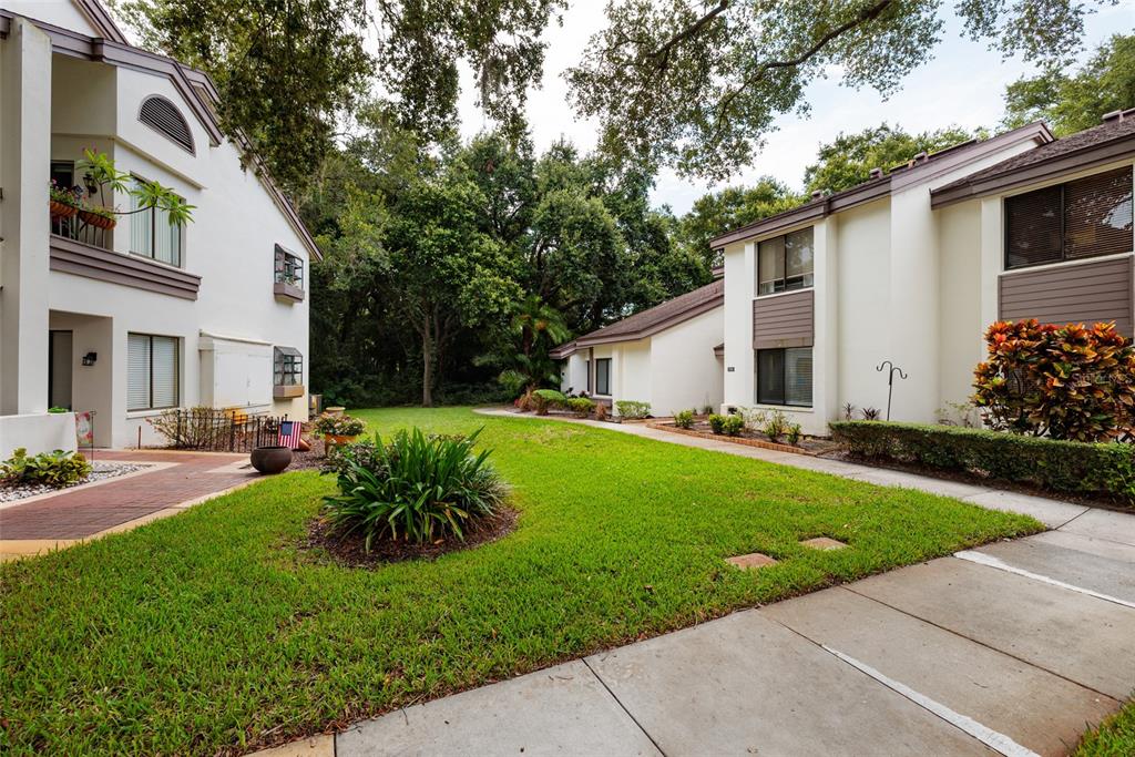 A view of a grassy courtyard between two multi-story apartment buildings with sidewalks — 1750 LAKE CYPRESS DRIVE UNIT 1002, SAFETY HARBOR, FL