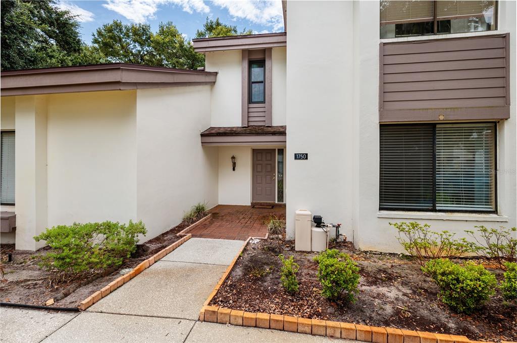 The exterior of a two-story home features a brick walkway leading to a recessed entrance — 1750 LAKE CYPRESS DRIVE UNIT 1002, SAFETY HARBOR, FL