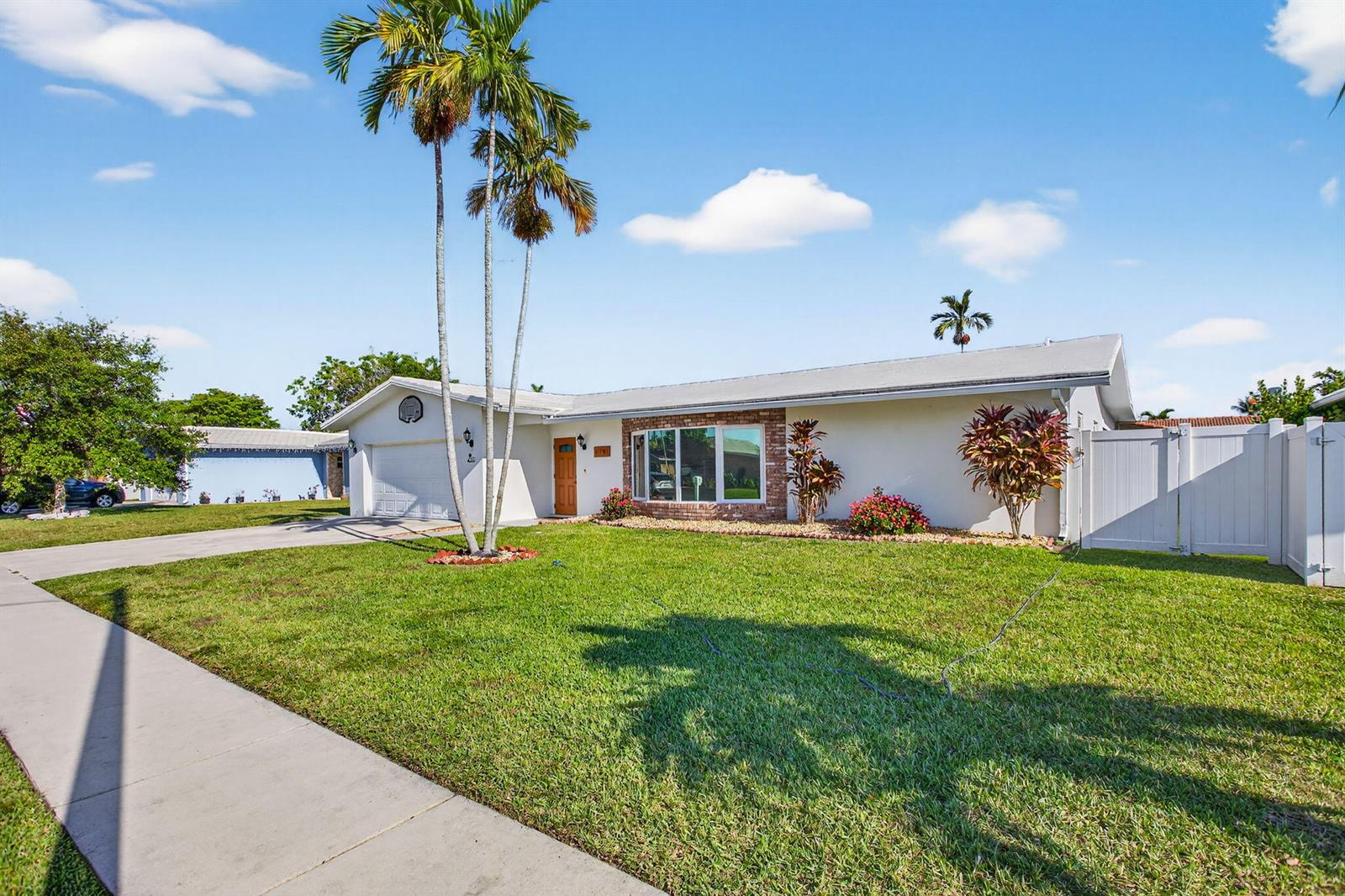 A single-story house with a white exterior, a brick-accented window, and tall palm trees — 6701 NW 20th Street, Margate FL 33063, MARGATE, FL
