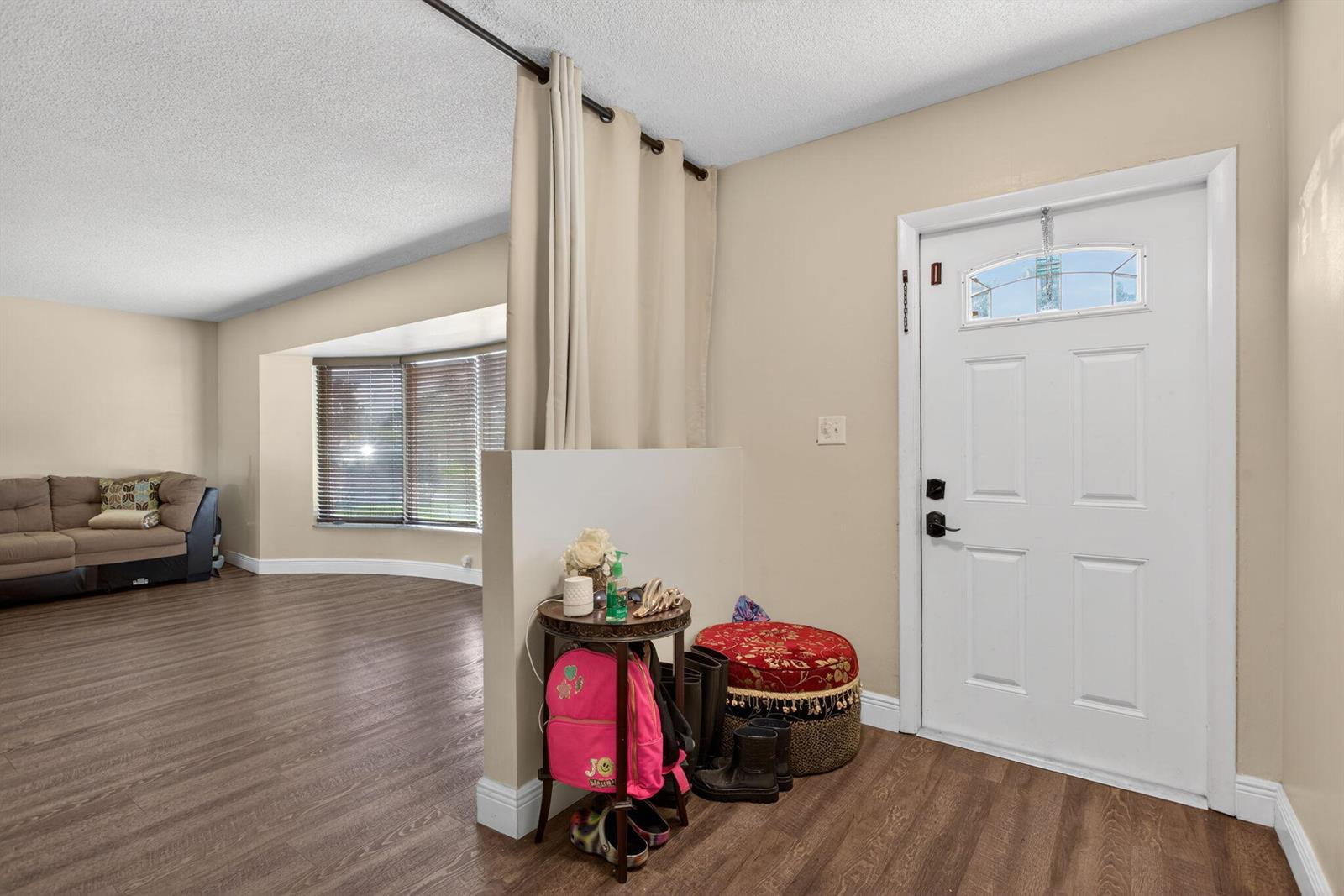 An entryway with a half-wall divider, curtain, and front door opens into a living room — 6701 NW 20th Street, Margate FL 33063, MARGATE, FL
