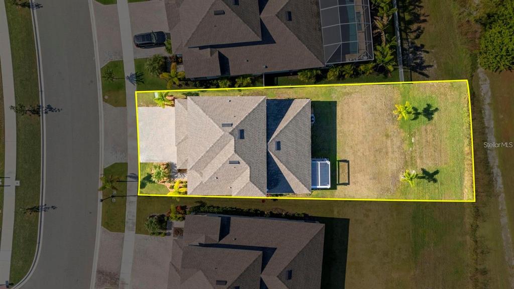 An aerial view shows a house with a large backyard enclosed by a yellow border — 933 SIGNET DRIVE, APOLLO BEACH, FL