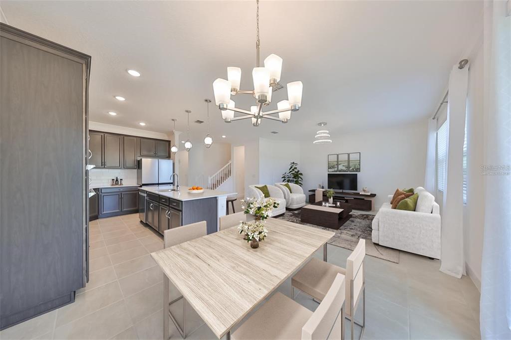 An open-concept kitchen, dining area, and living room with dark cabinetry and light tile flooring — 933 SIGNET DRIVE, APOLLO BEACH, FL