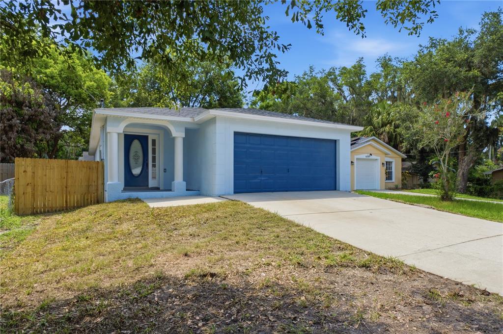 A light blue single-story house with a blue garage door and a matching front door — 6812 LYMAN AVENUE, TAMPA, FL