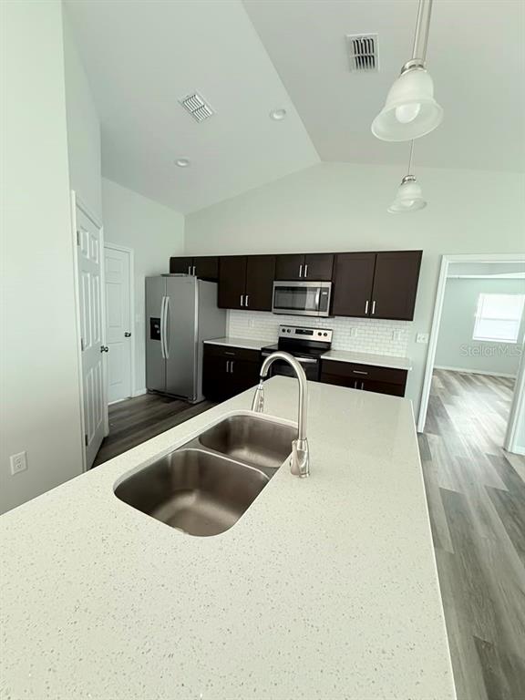 A kitchen features dark cabinetry, stainless steel appliances, a white quartz island, and light flooring — 6823 SW 129TH STREET, OCALA, FL