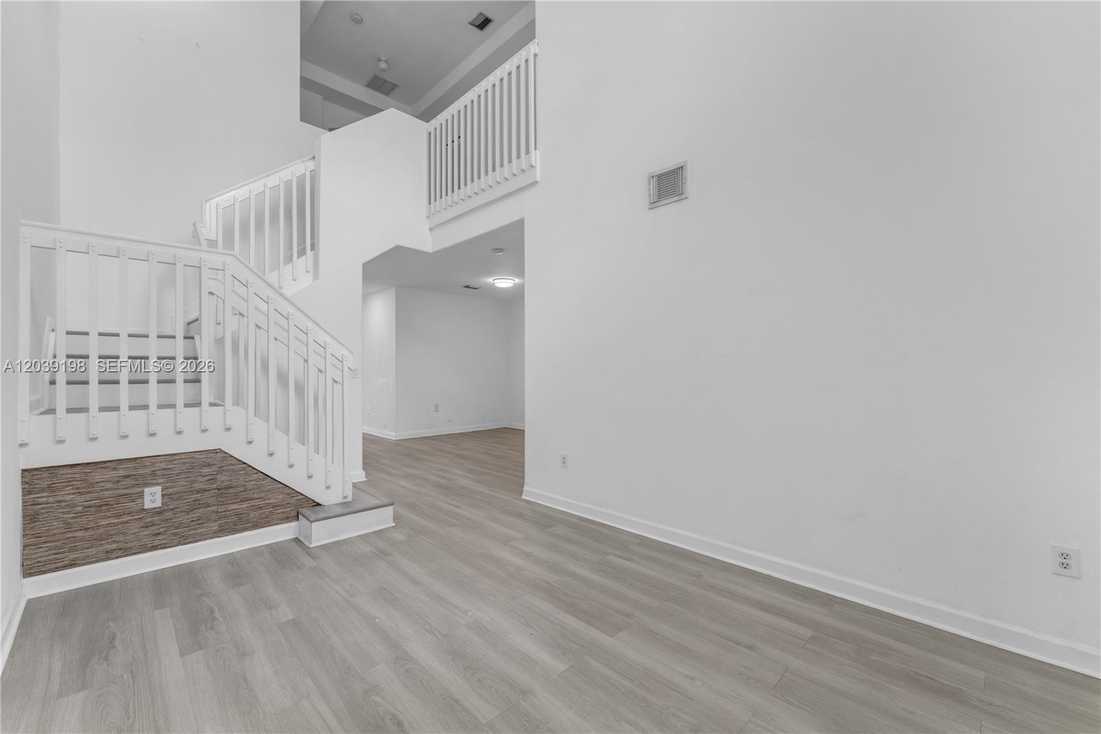 A bright room features a white staircase with a wood-accented base and light flooring — 14970 SW 9th Ter, Miami FL 33194, MIAMI, FL