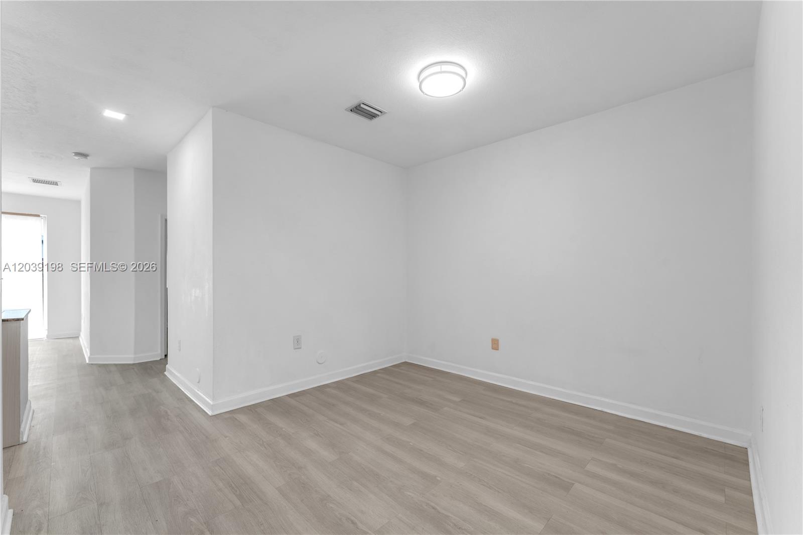 A bright, empty room features white walls, light wood-look flooring, and a ceiling light fixture — 14970 SW 9th Ter, Miami FL 33194, MIAMI, FL