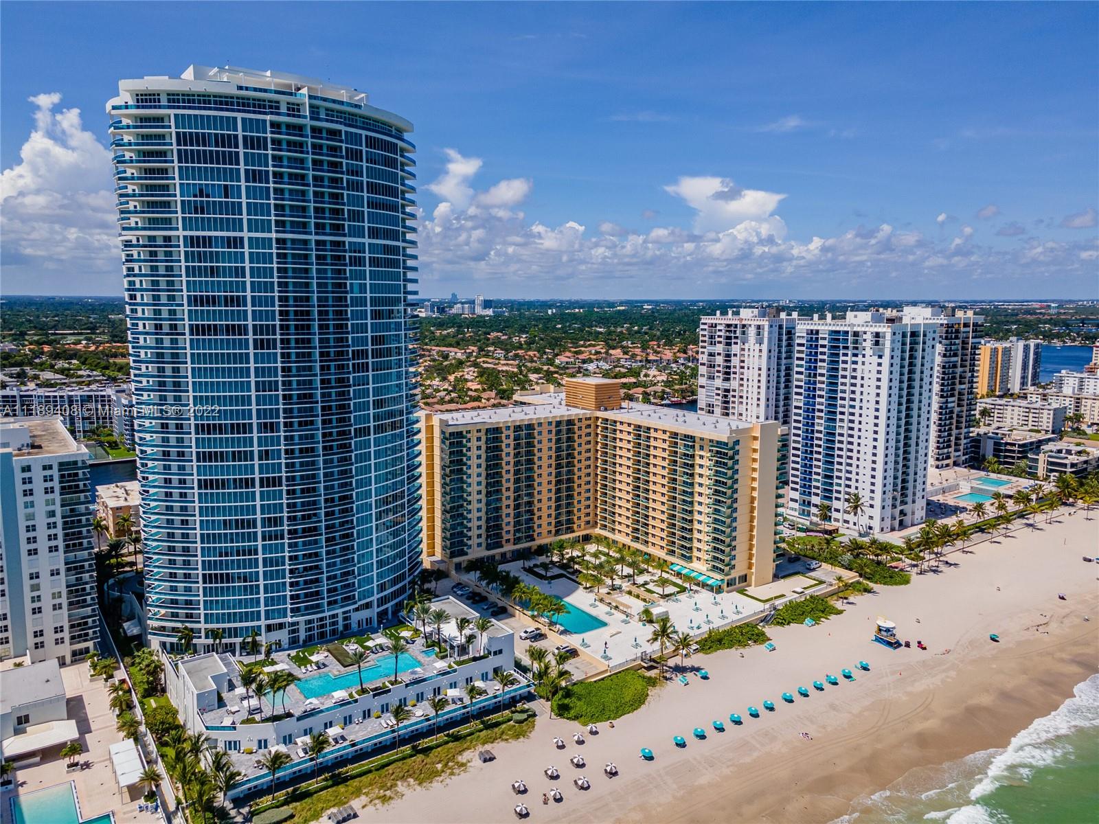 An aerial view shows high-rise residential buildings along a sandy beach with swimming pools — 2501 S OCEAN DR, Hollywood FL 33019, HOLLYWOOD, FL
