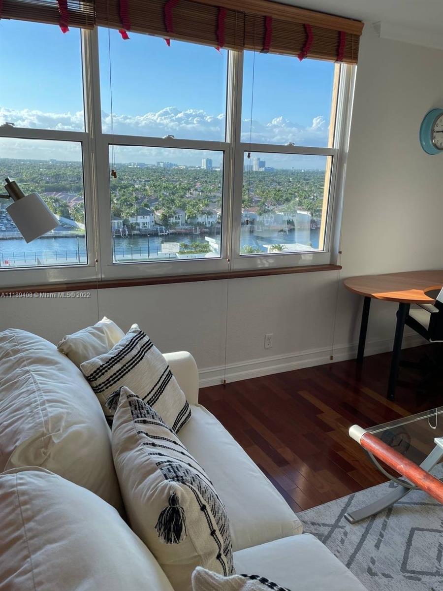 A living room with hardwood floors, a white sofa, and a large window overlooking water — 2501 S OCEAN DR, Hollywood FL 33019, HOLLYWOOD, FL
