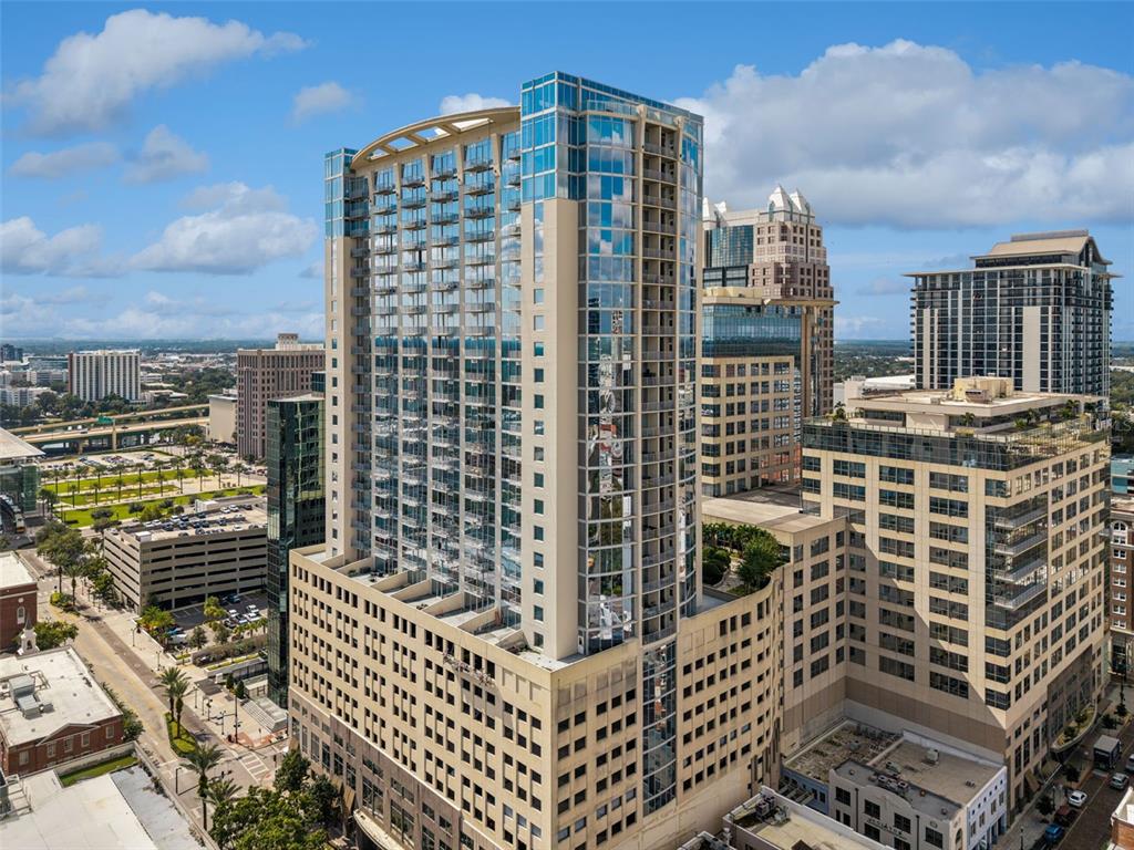 An aerial view of a tall, modern glass and concrete skyscraper in a city — 155 S COURT AVENUE UNIT P-2901, ORLANDO, FL