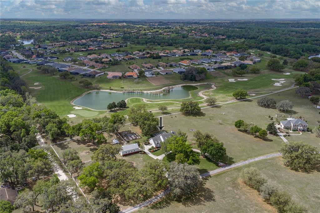 An aerial view shows a house with a pool enclosure situated on a large lot — 34428 MISSION VALLEY DRIVE, DADE CITY, FL