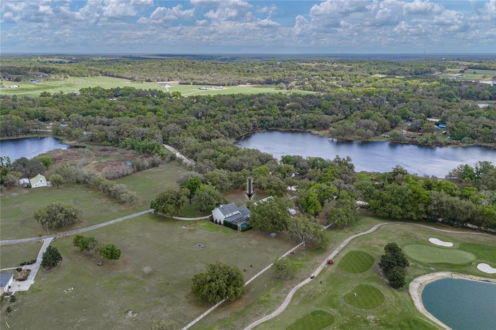 An aerial view shows a house with a pool situated on a large, grassy lot — 34428 MISSION VALLEY DRIVE, DADE CITY, FL