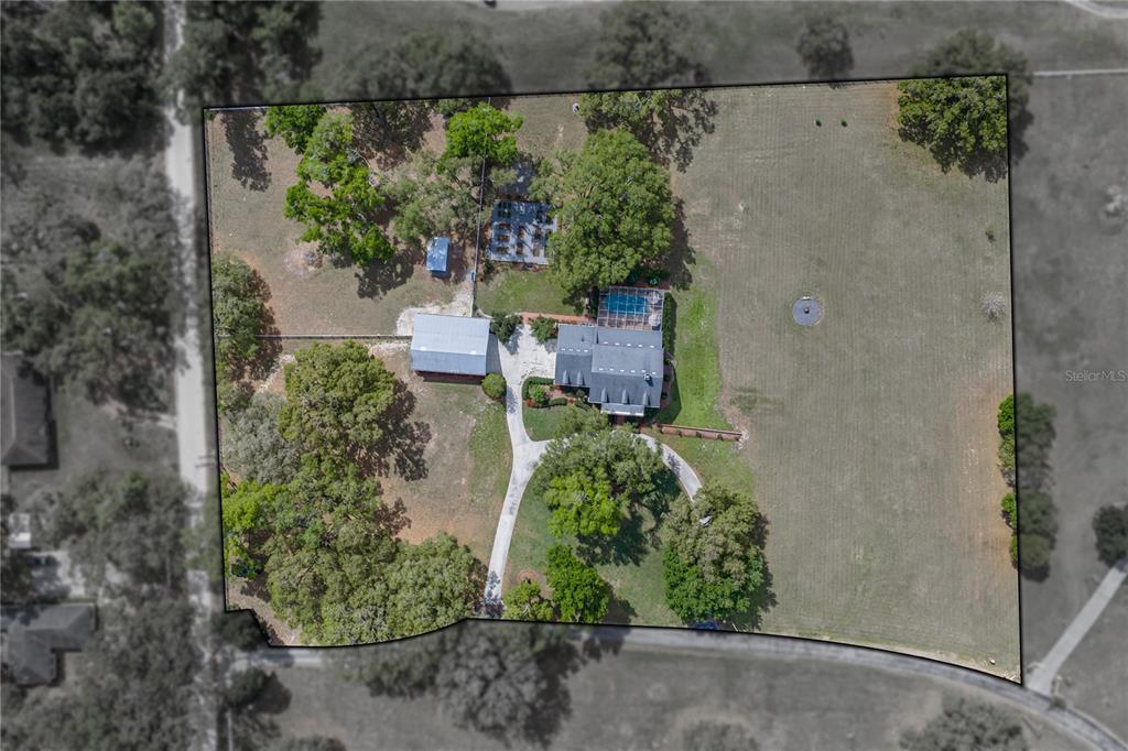 An aerial view shows a house with a pool, a detached garage, and surrounding land — 34428 MISSION VALLEY DRIVE, DADE CITY, FL