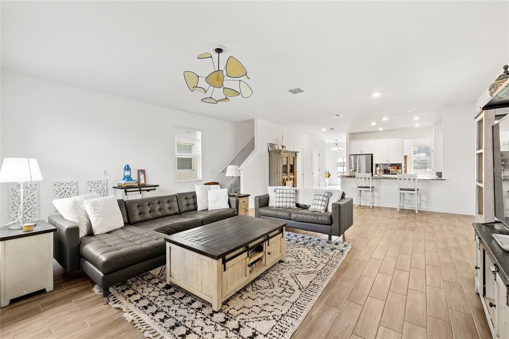 A living room with a sectional sofa, coffee table, and an open kitchen in back — 11442 LISTENING DRIVE, ORLANDO, FL