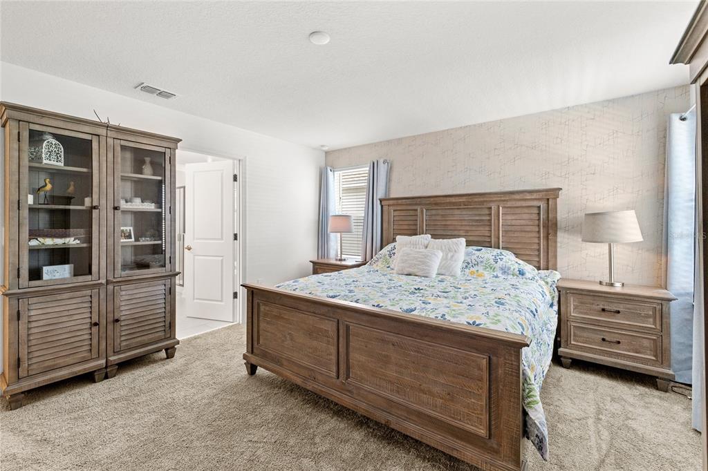 A bedroom features a wooden bed frame, matching nightstands, a tall display cabinet, and carpet — 11442 LISTENING DRIVE, ORLANDO, FL