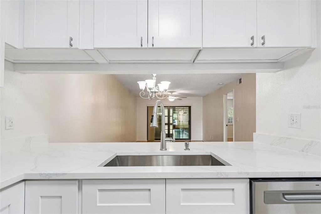 A kitchen sink with a gooseneck faucet is set into a white marble-look countertop — 723 83RD AVENUE N UNIT 104, ST PETERSBURG, FL