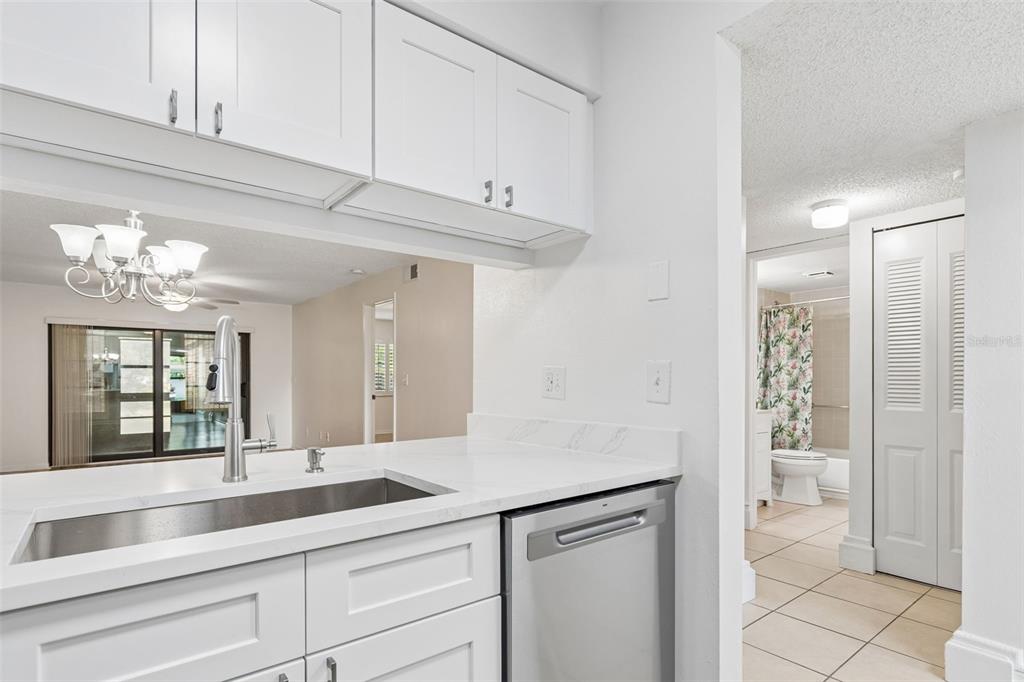 A kitchen features white cabinets, a stainless steel sink, and a dishwasher with tile flooring — 723 83RD AVENUE N UNIT 104, ST PETERSBURG, FL