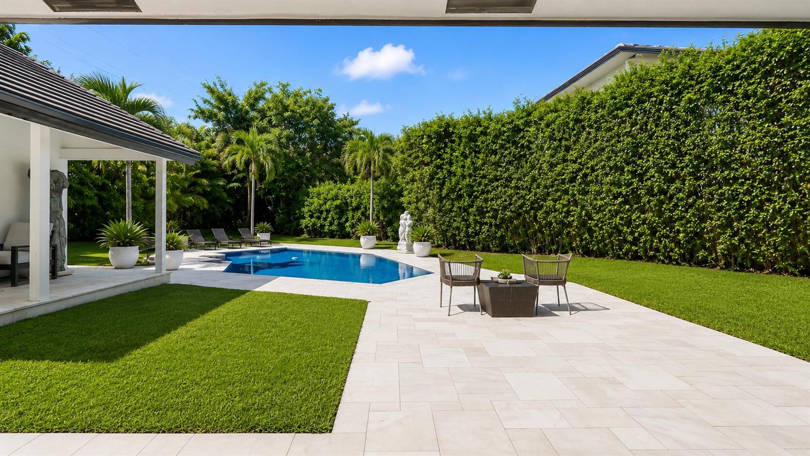 A backyard features a swimming pool, patio furniture, and a tall hedge bordering the lawn — 501 Sandpiper Way, Boca Raton FL 33431, BOCA RATON, FL