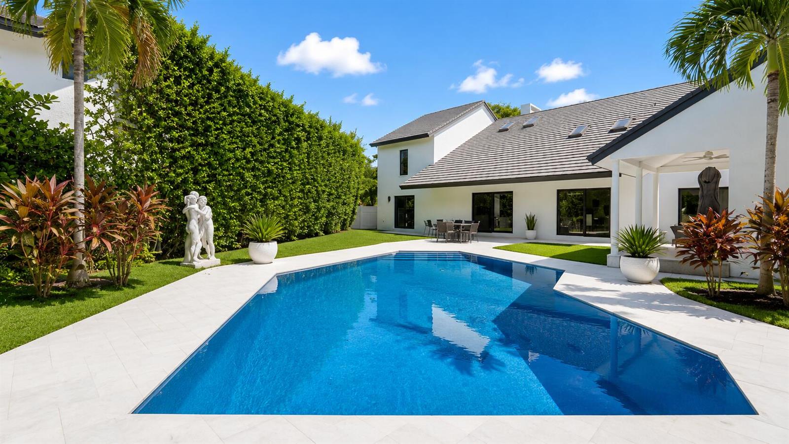 A backyard features a swimming pool, a white house, a tall hedge, and palm trees — 501 Sandpiper Way, Boca Raton FL 33431, BOCA RATON, FL