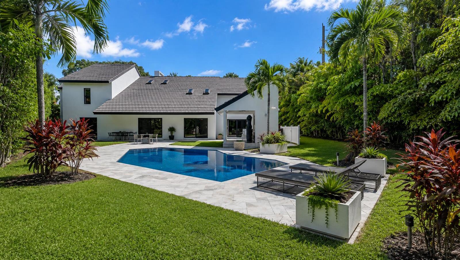 A white two-story house features a backyard swimming pool, stone patio, and lush tropical landscaping — 501 Sandpiper Way, Boca Raton FL 33431, BOCA RATON, FL