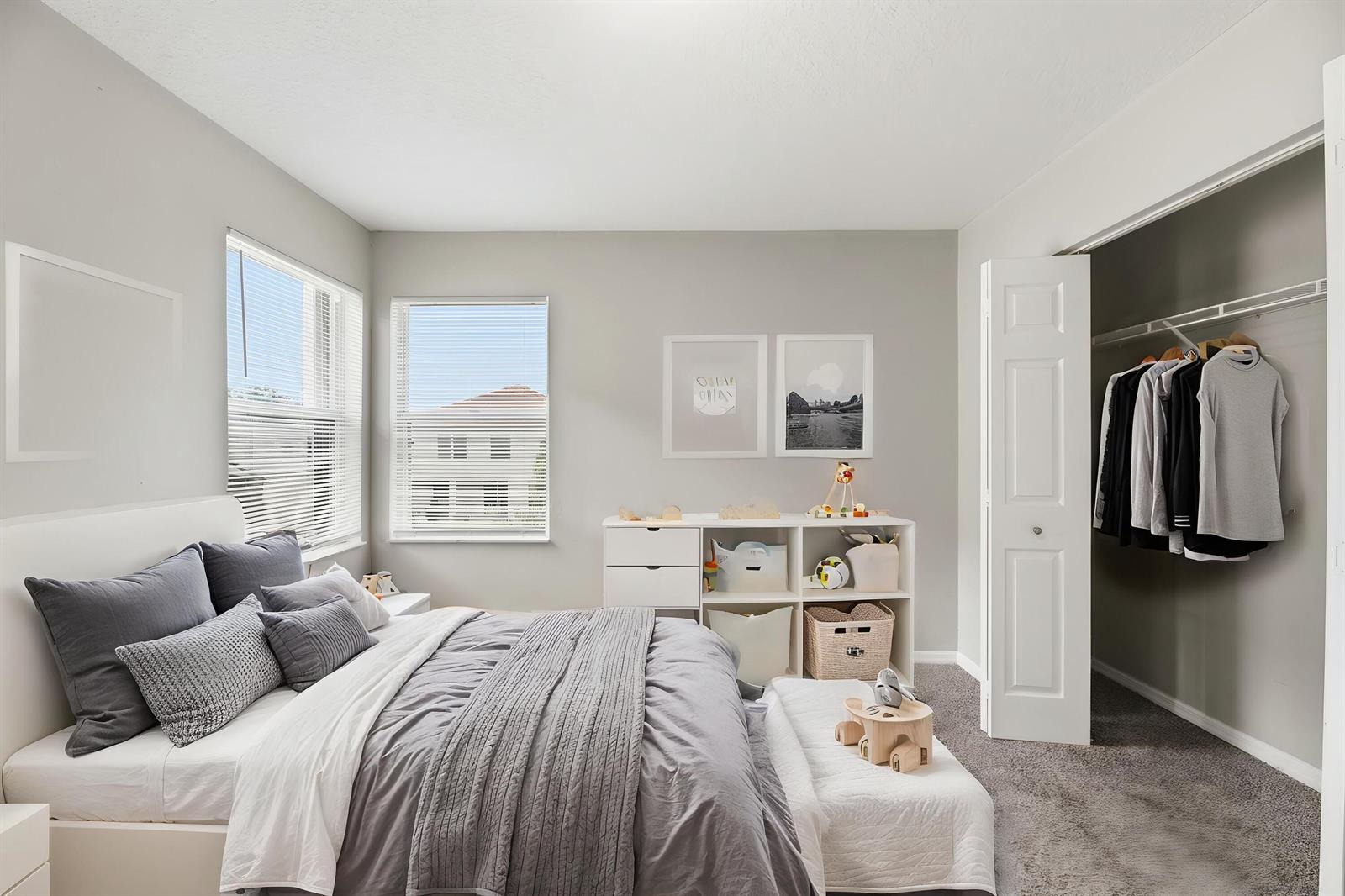 A bedroom features a bed with grey bedding, a white storage unit, and a walk-in closet — 7634 Trenton Drive, Lake Worth FL 33467, LAKE WORTH, FL