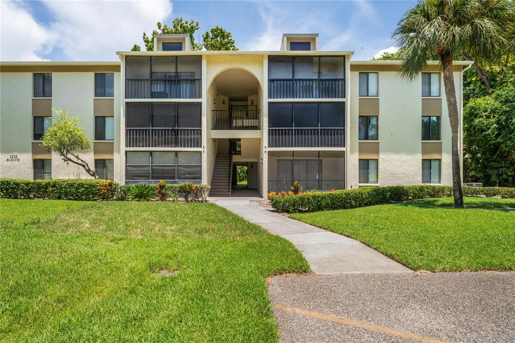 A three-story apartment building with screened balconies and a central outdoor staircase — 3232 LAKE PINE WAY UNIT H2, TARPON SPRINGS, FL