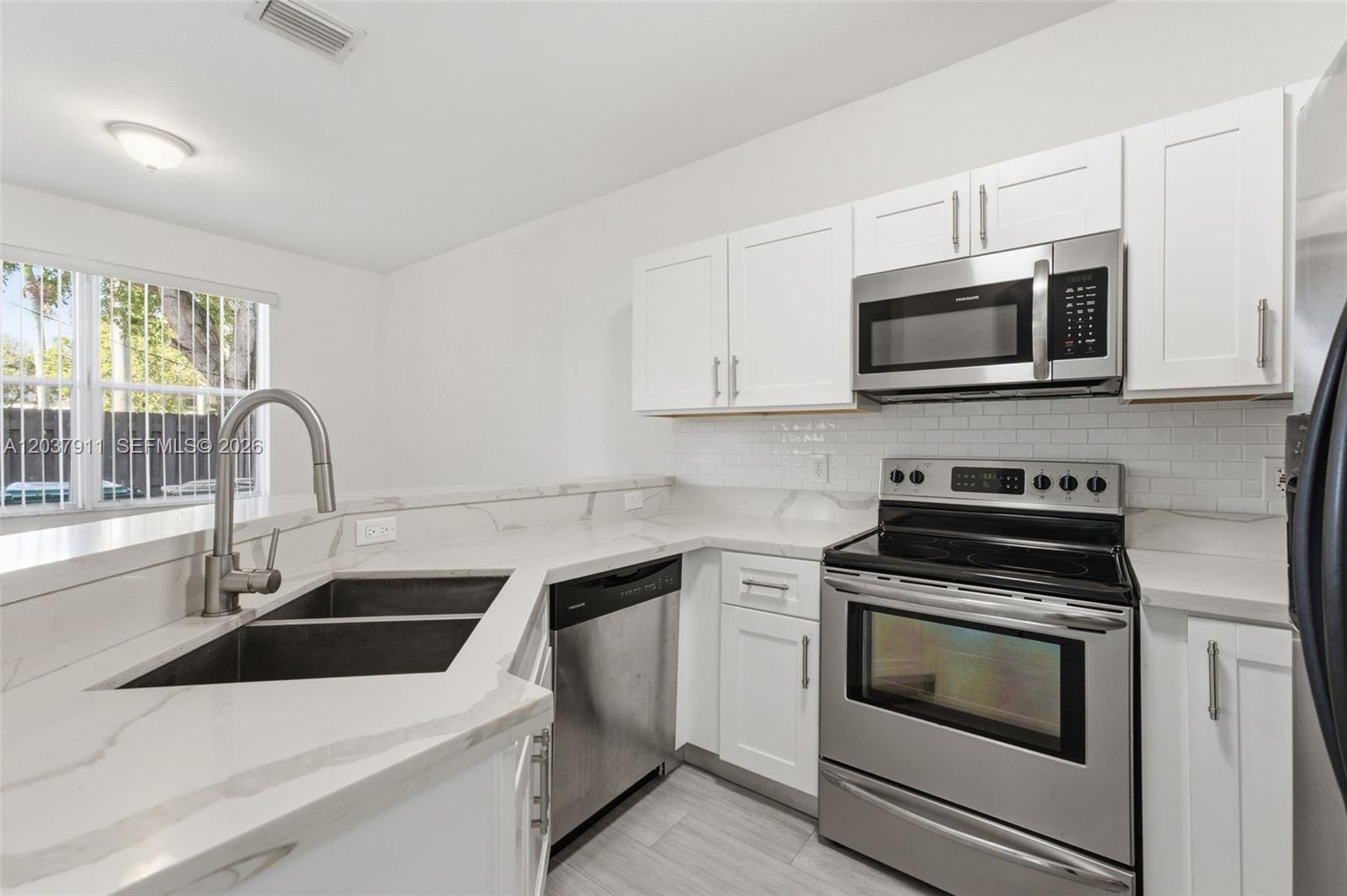 A kitchen features white cabinets, stainless steel appliances, and white marble-look countertops — 12594 SW 122nd St, Miami FL 33186, MIAMI, FL