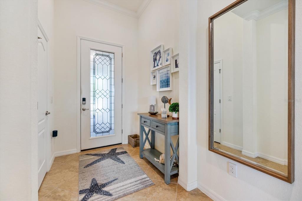 A bright entryway features a front door with glass panels, a console table, and mirror — 19393 CRUISE DRIVE, VENICE, FL