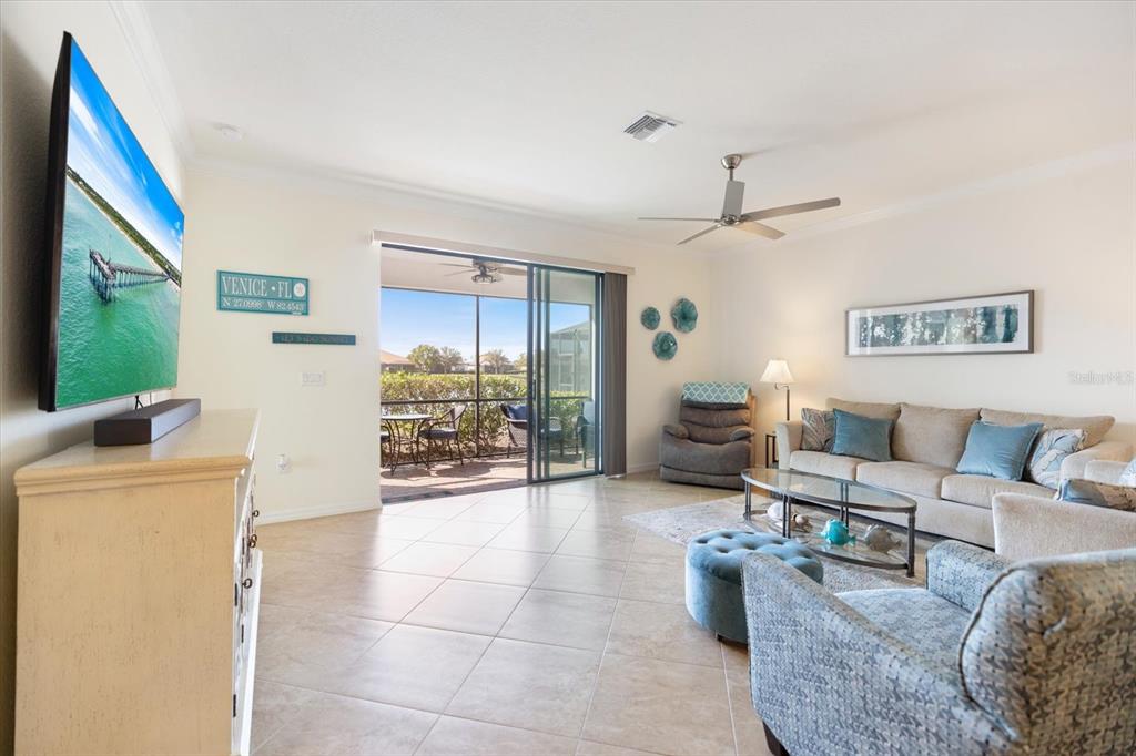 A living room features tile flooring, a television, a sofa, and a sliding glass door — 19393 CRUISE DRIVE, VENICE, FL