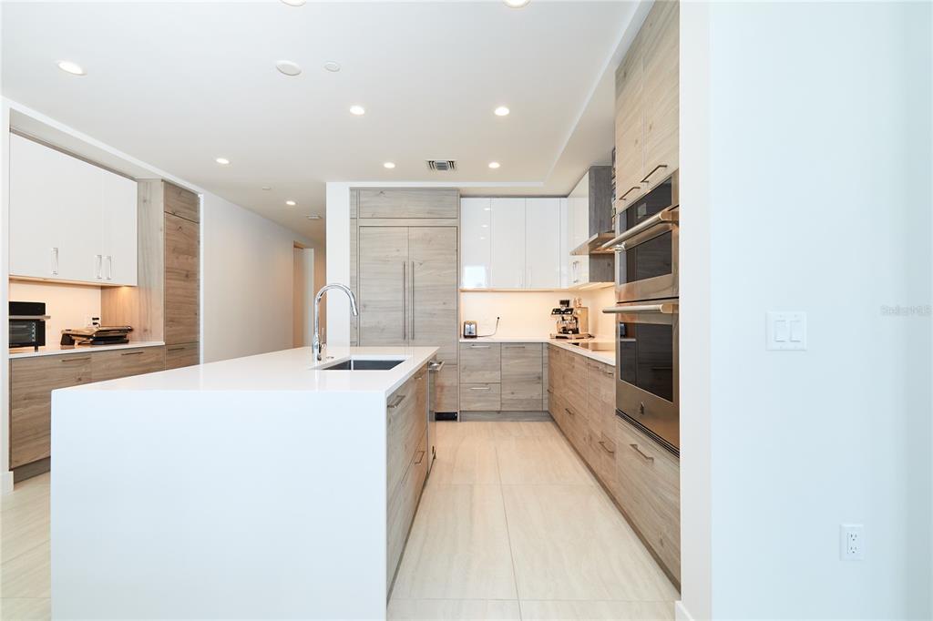 A modern kitchen features white and wood-grain cabinetry, a large island, and stainless steel appliances — 301 1ST STREET S UNIT 804, ST PETERSBURG, FL