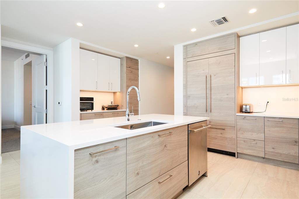 A modern kitchen features light wood cabinetry, white countertops, a central island, and stainless steel appliances — 301 1ST STREET S UNIT 804, ST PETERSBURG, FL