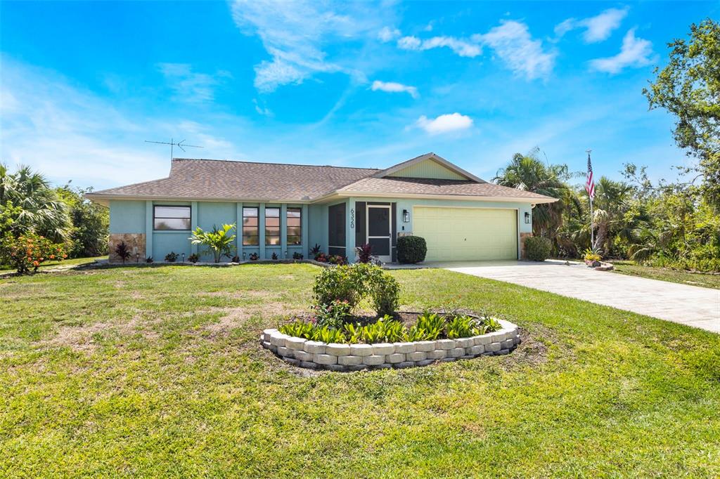 A single-story house with a light blue exterior, a two-car garage, and a landscaped yard — 6320 BROOKRIDGE STREET, ENGLEWOOD, FL