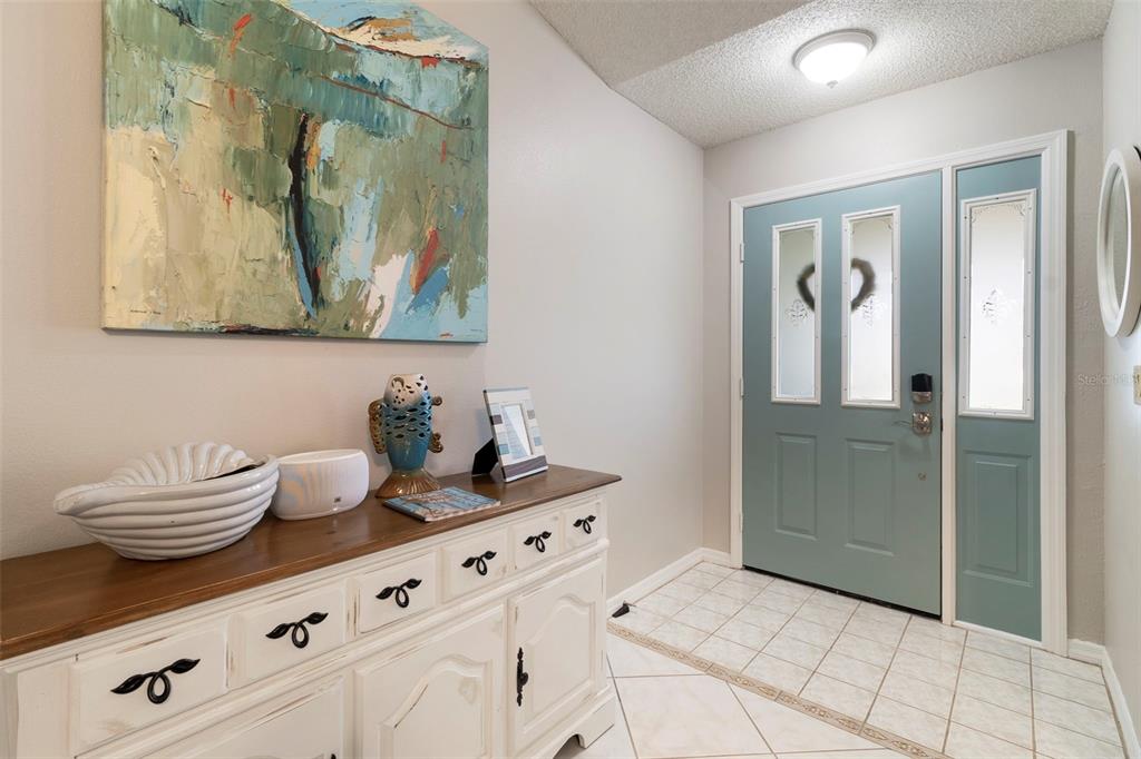 An entryway features a white wooden cabinet, a blue abstract painting, and a teal door — 6320 BROOKRIDGE STREET, ENGLEWOOD, FL
