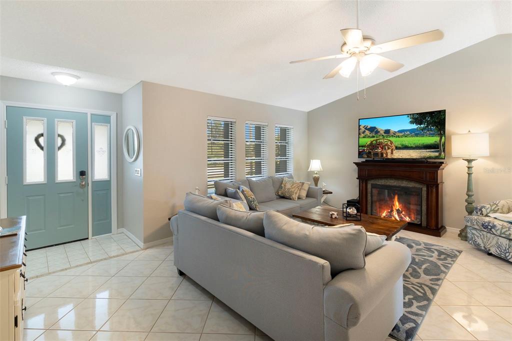A living room features a fireplace, a sectional sofa, tile flooring, and a blue door — 6320 BROOKRIDGE STREET, ENGLEWOOD, FL