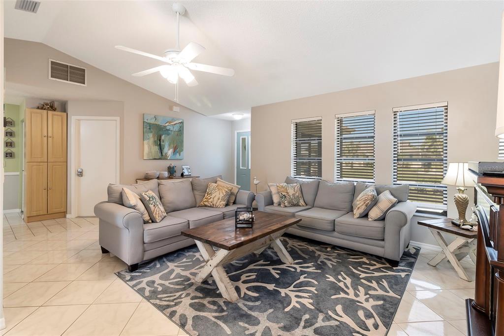 A living room features two gray sofas, a wooden coffee table, and a coral-patterned rug — 6320 BROOKRIDGE STREET, ENGLEWOOD, FL