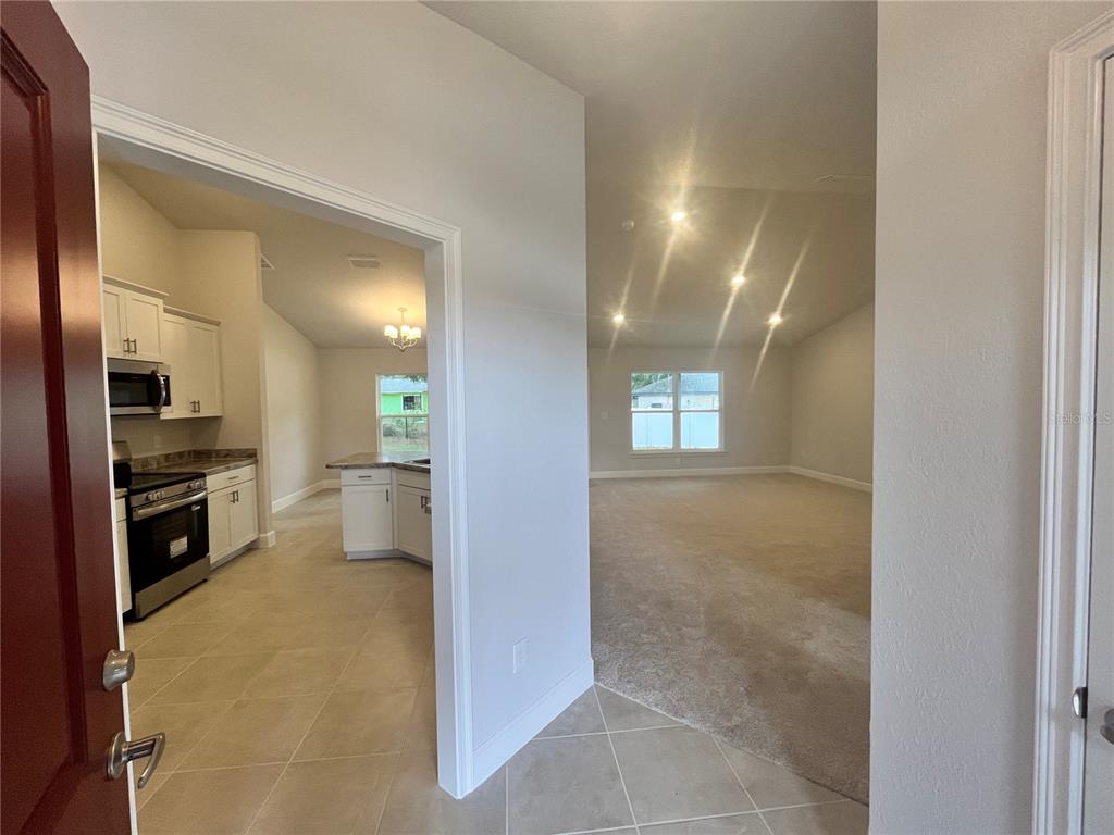 A view from an entryway looking into a kitchen with white cabinets and a living area — 7 BAHIA PASS LANE, OCALA, FL