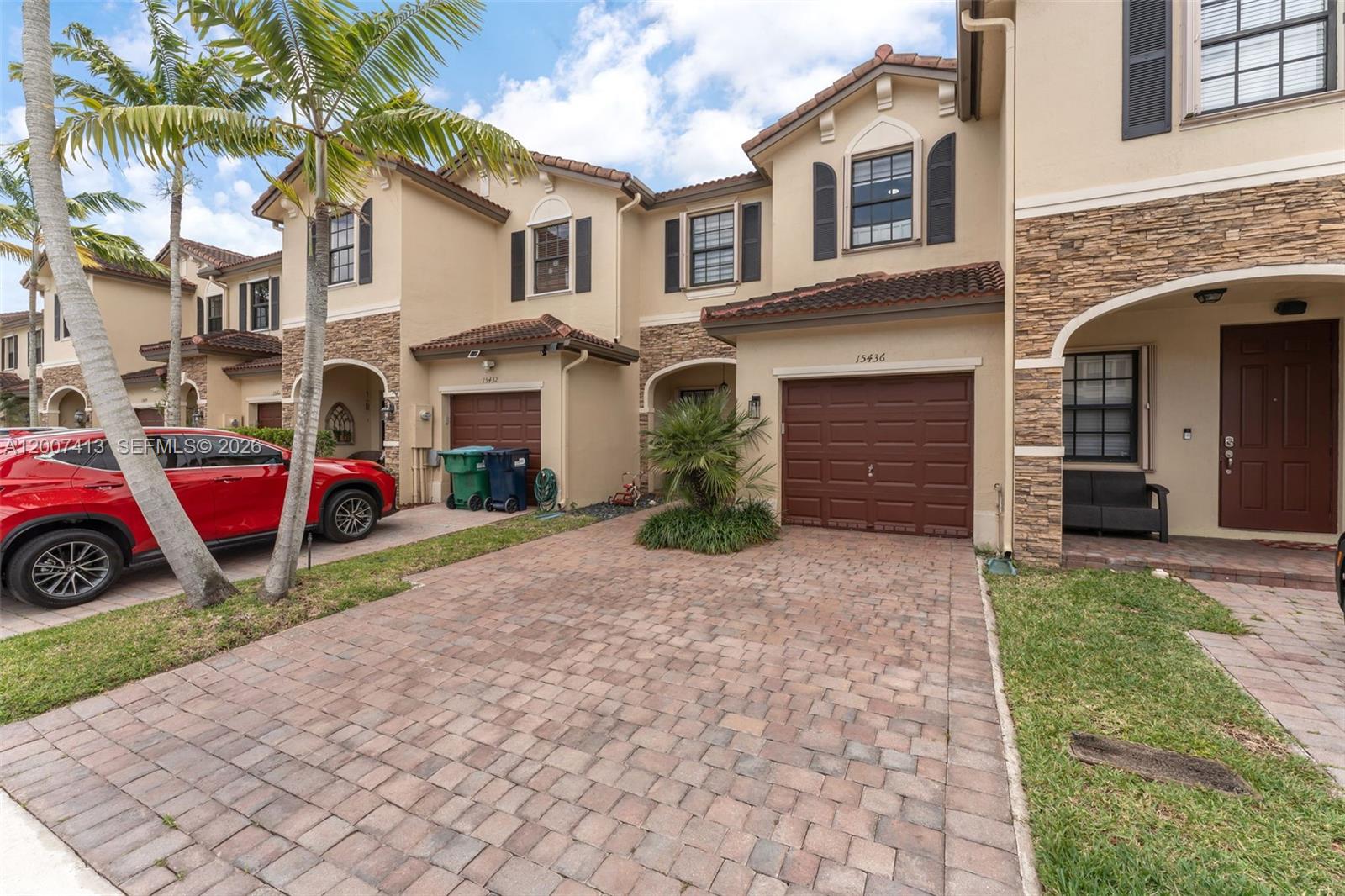 A row of two-story townhouses features brick paver driveways, brown garage doors, and stone accents — 15436 SW 119th Ter, Miami FL 33196, MIAMI, FL