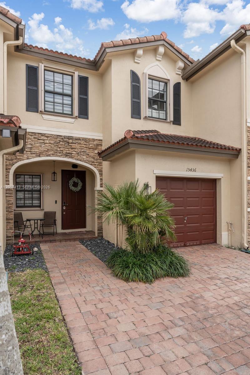 A two-story townhouse exterior features a brick paver driveway, a small palm tree, and a garage — 15436 SW 119th Ter, Miami FL 33196, MIAMI, FL