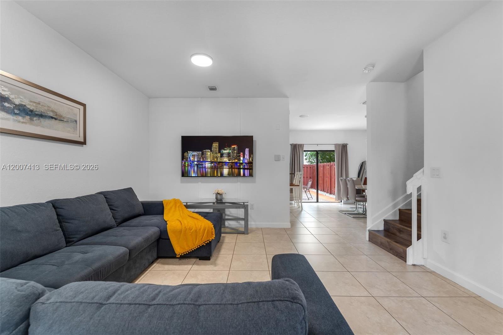 A living room features a grey sectional sofa, a wall-mounted television, and tiled flooring — 15436 SW 119th Ter, Miami FL 33196, MIAMI, FL