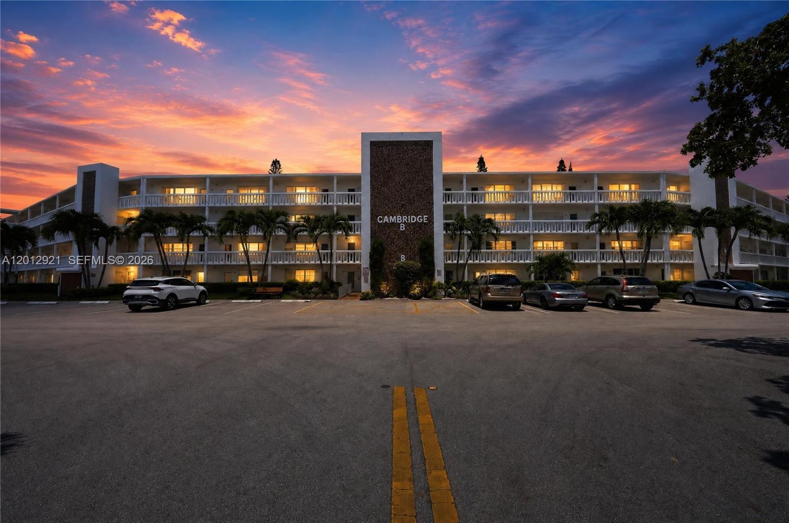 A multi-story apartment building with a parking lot in the foreground at sunset — 3023 Cambridge B # 3023, Deerfield Beach FL 33442, DEERFIELD BEACH, FL
