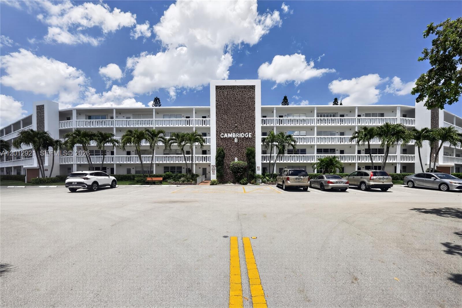 A multi-story apartment building with a central stone facade and a parking lot — 3023 Cambridge B # 3023, Deerfield Beach FL 33442, DEERFIELD BEACH, FL