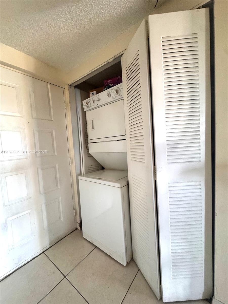 A stacked washer and dryer unit is located inside a closet next to a door — 8290 Lake Dr # 506, Doral FL 33166, DORAL, FL