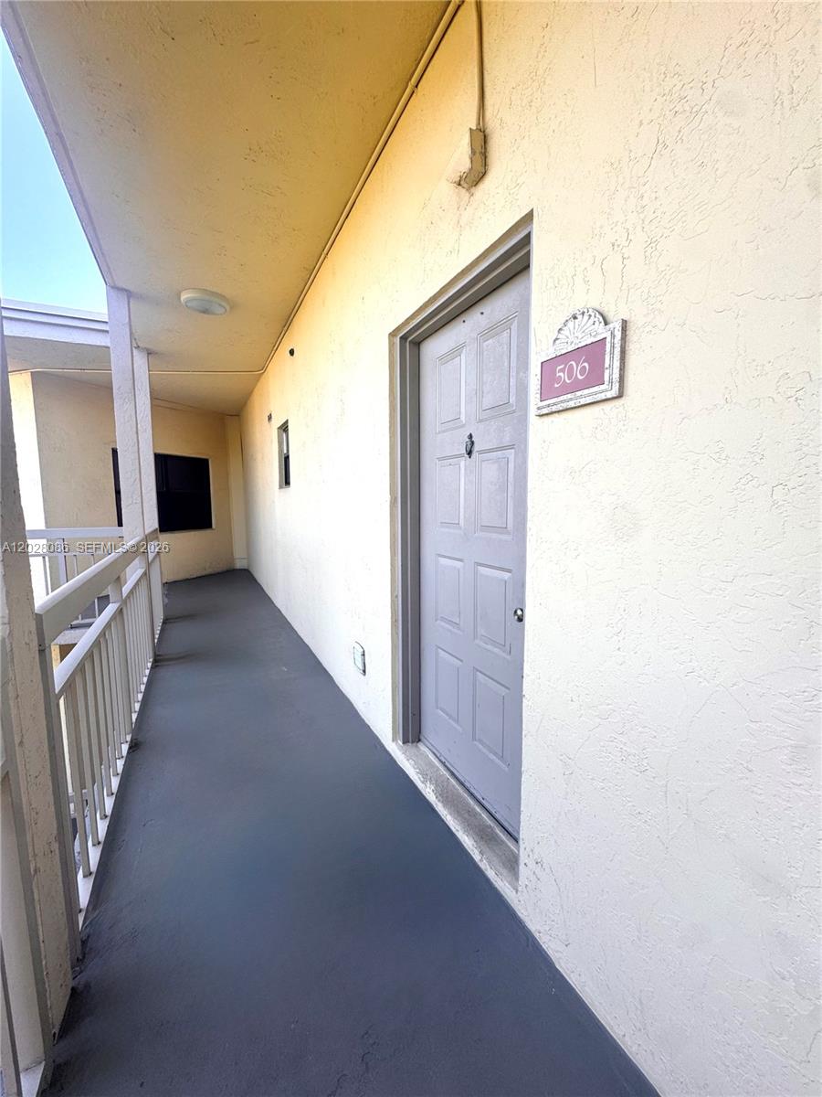 An exterior walkway leads to a gray apartment door marked with the number 506 — 8290 Lake Dr # 506, Doral FL 33166, DORAL, FL