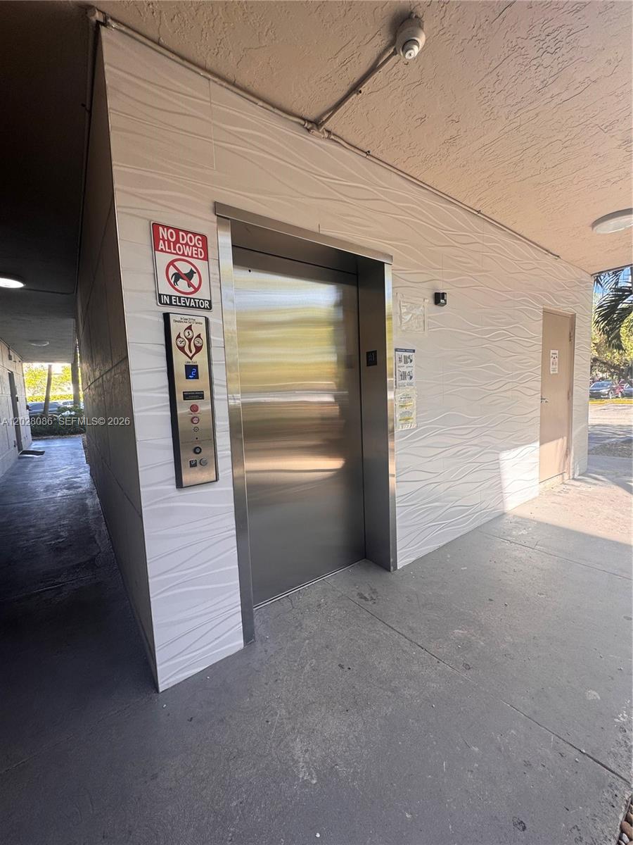 An elevator with a no-dog sign is located on a textured exterior wall — 8290 Lake Dr # 506, Doral FL 33166, DORAL, FL