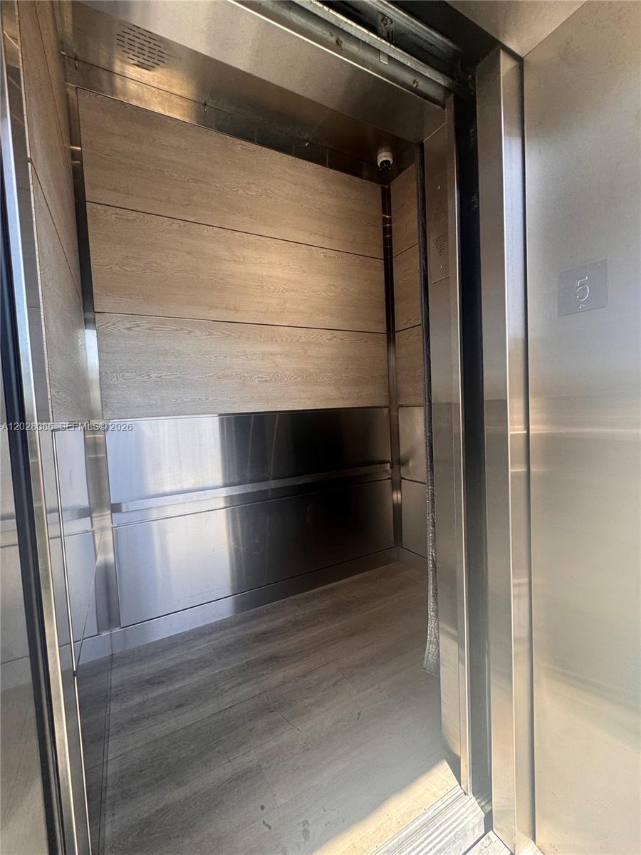 An elevator interior features wood-look wall panels, stainless steel accents, and wood-grain flooring — 8290 Lake Dr # 506, Doral FL 33166, DORAL, FL
