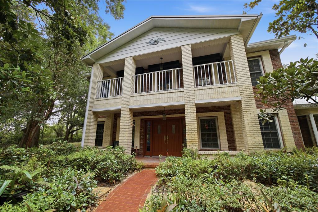 A two-story brick house features a covered front porch, balcony, and a brick walkway — 2271 KEYSTONE ROAD, TARPON SPRINGS, FL