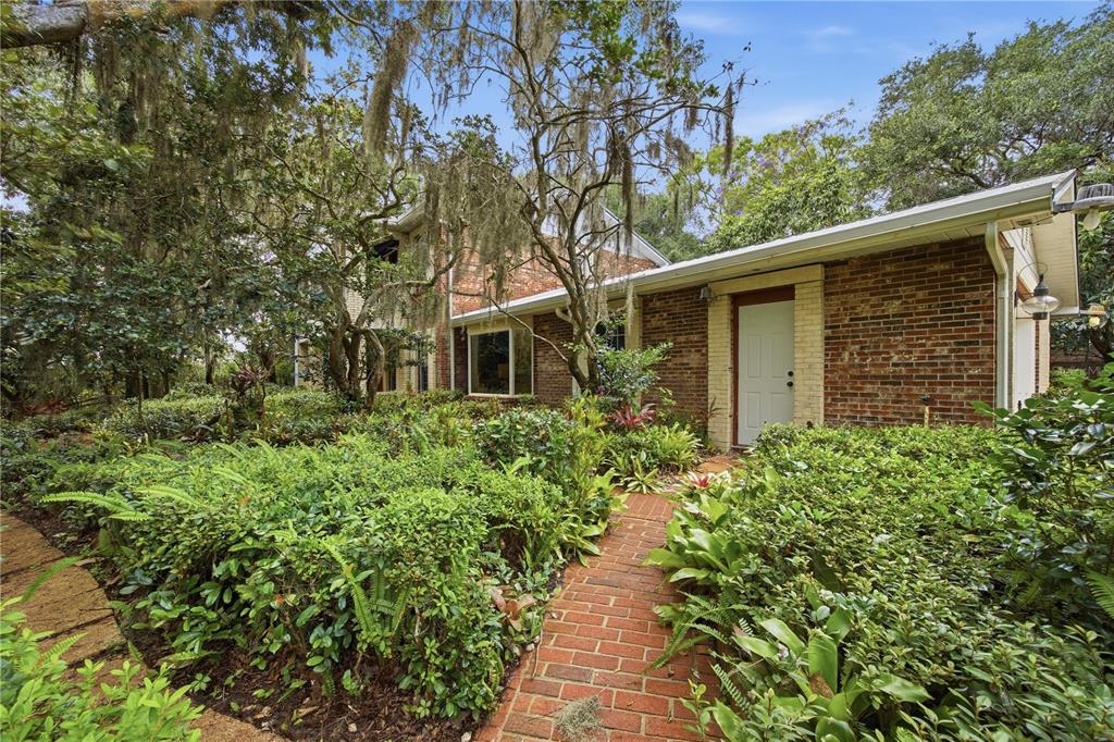 A brick house with a brick walkway surrounded by lush greenery and hanging moss — 2271 KEYSTONE ROAD, TARPON SPRINGS, FL
